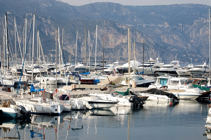 Port du littoral des Alpes-Maritimes avec voiliers et relief montagneux, illustration d’un territoire entre mer et altitude.
